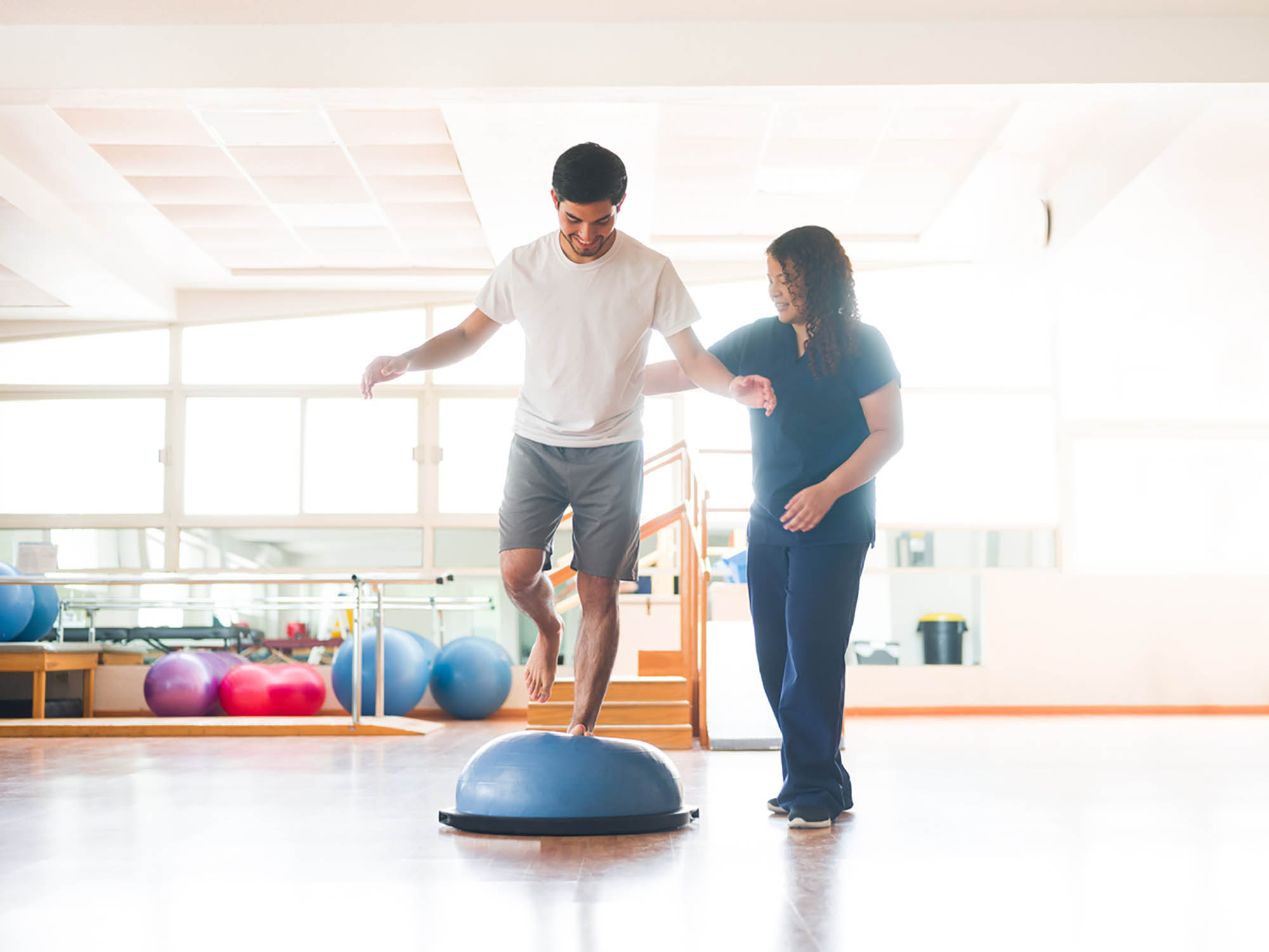Male physical rehab patient standing on bosu ball